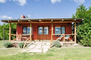 a red cottage with a porch and two chairs at Cabañas Luna Lunera in Tandil
