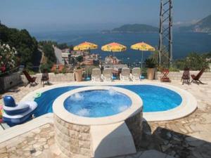 una piscina con sillas, sombrillas y agua en Villa Royal Dream, en Sveti Stefan