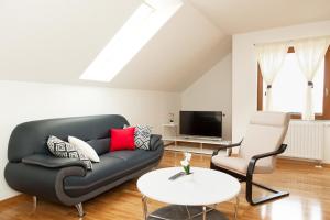 a living room with a black couch and a chair at Apartment Lena in Gornji Vaganac