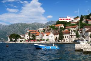 a blue boat in the water in front of a town at Apartments Jovanović in Perast
