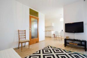 a living room with a flat screen tv and a chair at Leut Apartment, 3min beach, 15min center in Pula