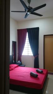 1 dormitorio con cama roja y ventilador de techo en Ila Homestay, en Senawang