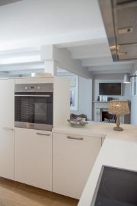 a kitchen with white cabinets and a stove at Das ELBCOTTAGE in Hamburg