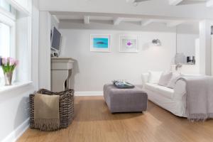 a white living room with a couch and a chair at Das ELBCOTTAGE in Hamburg