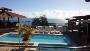 una piscina con sillas y el océano en el fondo en Laina´s Place Hotel, en Natal