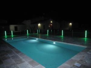una piscina vacía por la noche con luces verdes en Gite Les Courlis, en Saint-Étienne-du-Grès