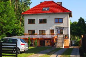 een huis met een rood dak en een auto aan de voorkant bij Willa BALTAZAR in Lubniewice