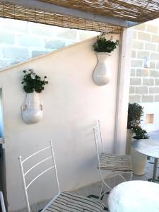 two white vases on a wall with two chairs and a table at Casa Sultana in Favignana