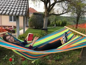 a woman laying in a hammock reading a book at Holiday Home Stella in Vrdnik