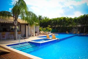 a swimming pool with chairs and a palm tree at Hotel Don Quijote Búzios in Búzios