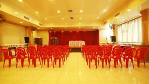 Una sala de conferencias con sillas rojas y un escenario con una mesa. en Hotel Palace Tower, en Trichūr
