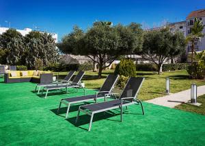 
a row of green lawn chairs sitting on top of a green lawn at B&B Hotel Valencia Ciudad de las Ciencias in Valencia
