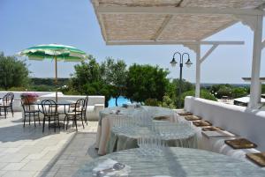 a patio with tables and chairs and an umbrella at Hotel Incanto in Ostuni