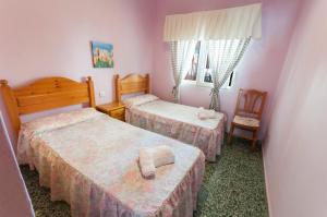Playa de MiramarにあるPandora 1のベッド2台と椅子が備わる小さな客室です。