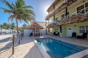 um resort com piscina e palmeiras em The Palapa House em San Pedro