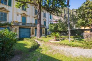 a large building with a garage and trees in a yard at Le Camerine Apartment Water Front in Toscolano Maderno
