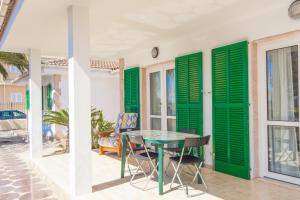 a patio with green shutters and a table and chairs at Rodriguez De La Fuente 19 (Sin Nombre) in Playa de Muro