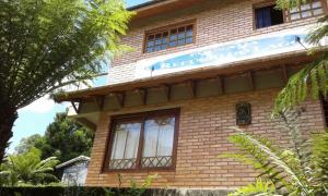 a brown brick building with a sign on it at Pousada Refúgio do Lago in São Francisco de Paula