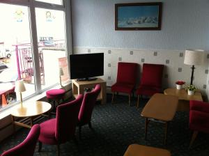 uma sala de espera com cadeiras vermelhas e uma televisão de ecrã plano em Howard Hotel em Blackpool