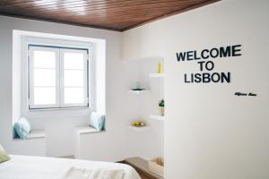 um quarto branco com uma janela e um sinal de boas-vindas para Lisboa em Alfama Apartment Rose - Guitarra em Lisboa