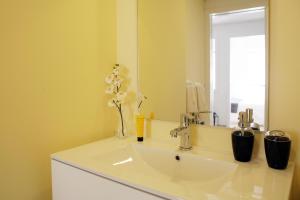 W łazience znajduje się biała umywalka i lustro. w obiekcie Alfama Rose Apartment - Elétrico w Lizbonie