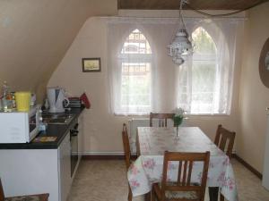 a kitchen with a table with chairs and a kitchen with two windows at Pension und Ferienwohnung Christine Kilian in Eisenach