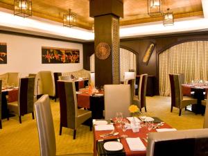 The Gateway Hotel Beach Road Visakhapatnam في فيساخاباتنام: مطعم فيه طاولات وكراسي في الغرفة