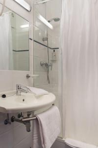 a bathroom with a sink and a shower curtain at Aero44 Hotel Charleroi Airport in Charleroi