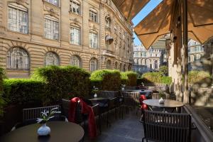 a patio with tables and chairs in front of a building at Le Pavillon des Lettres in Paris