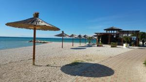 une plage de sable avec des parasols et l'océan dans l'établissement Apartments Babić, à Fažana