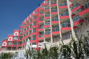 um grande edifício vermelho com cadeiras em frente em Angel Apartment - Kalina Angelova em Sunny Beach