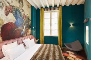 una camera da letto con un letto e un dipinto sul muro di Hotel du Petit Moulin a Parigi