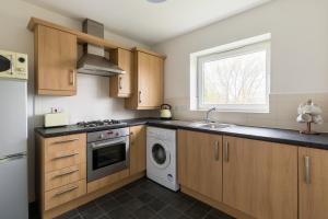 una cucina con armadi in legno, lavandino e lavastoviglie di Wolverhampton City Stay a Wolverhampton