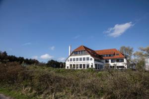 a large white house sitting on top of a hill at Fletcher Boutique Hotel Duinoord in Wassenaar