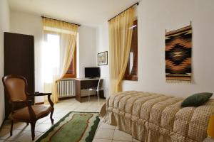 a bedroom with a bed and a chair and a television at Il Terrazzo B&B in Romagnano Sesia