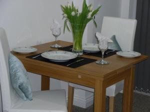 een houten tafel met borden en glazen en een vaas met bloemen bij Almondsbury Luxury Apartment in Almondsbury