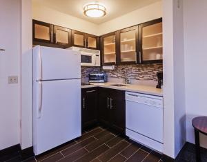 a kitchen with a white refrigerator and wooden cabinets at Staybridge Suites Tulsa-Woodland Hills, an IHG Hotel in Tulsa