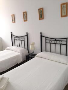 two beds in a bedroom with white walls at Hostal Rios in Bolonia