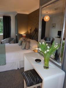 Almondsbury Luxury Apartment في ألموندسبيري: غرفة في الفندق بها سرير و مزهرية من الزهور