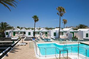 a pool at a resort with palm trees and buildings at Apartamentos LIVVO Las Gaviotas in Puerto del Carmen