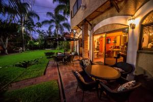 an outdoor patio with tables and chairs and a lawn at Hotel La Mansion del Sol in Guadalajara