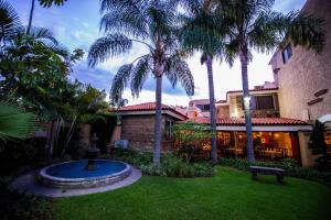 a house with a fountain in a yard with palm trees at Hotel La Mansion del Sol in Guadalajara