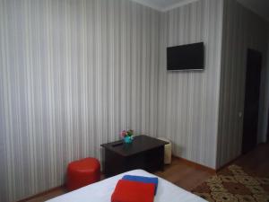 Habitación de hotel con cama y TV en la pared en Tumar en Bishkek