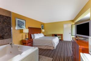 a hotel room with a bed and a tub and a television at Lodge at Mill Creek Pigeon Forge in Pigeon Forge