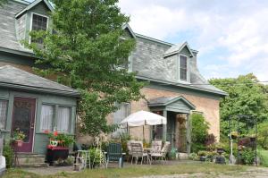 a house with chairs and an umbrella in the yard at Sommerville Court Motel Bed & Breakfast in Lucknow