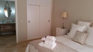 Un dormitorio con una cama blanca con toallas. en Apartamento La Judería de San Clemente, en Sevilla