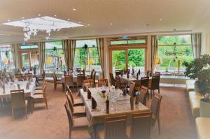 a dining room with tables and chairs and windows at Hotel & Restaurant Kronenhof am Weser-Radweg in Oedelsheim
