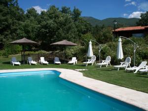 a swimming pool with chairs and umbrellas and a group of chairs at Apartamentos El Roble in Valverde de la Vera