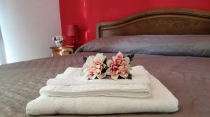 a pile of towels and flowers on a bed at Le Due Palme House in Torre San Giovanni Ugento