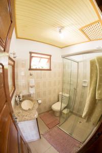 uma casa de banho com um chuveiro, um lavatório e um WC. em Pouso Lar Doce Lar em Tiradentes
